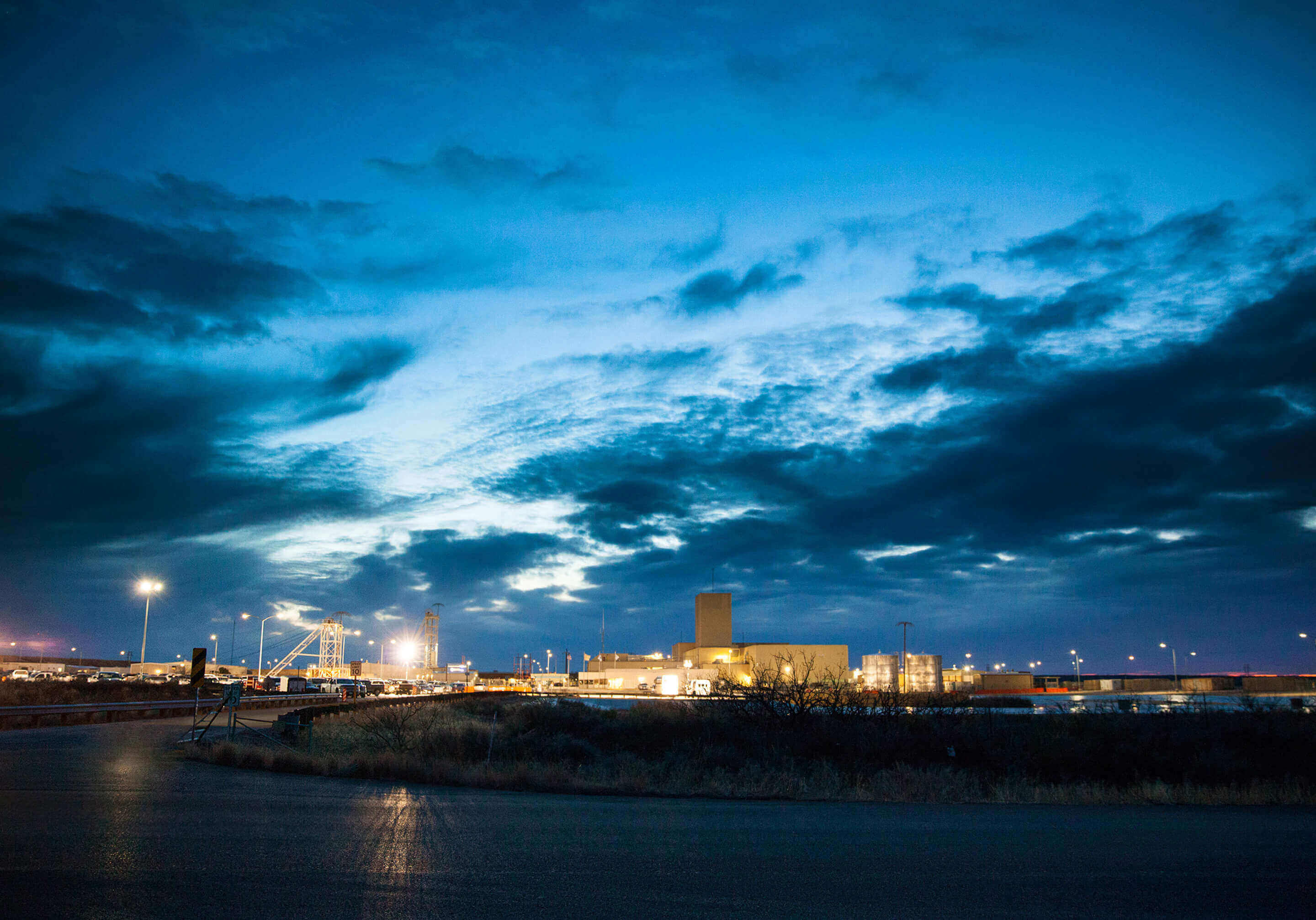 Landscape image of the Waste Isolation Pilot Plant at dusk with with dark blue clouds overhead