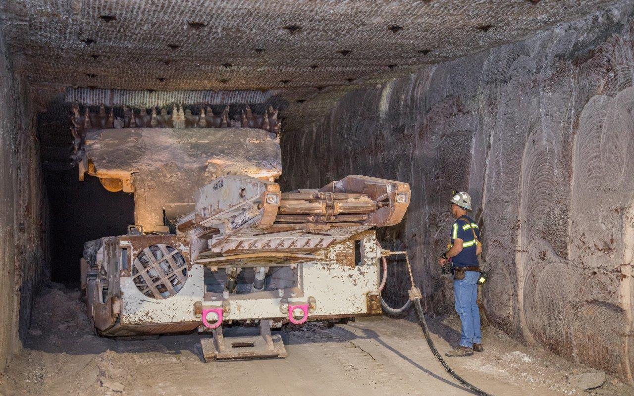 photo of a continuous mining machine with operator cutting the back of a panel